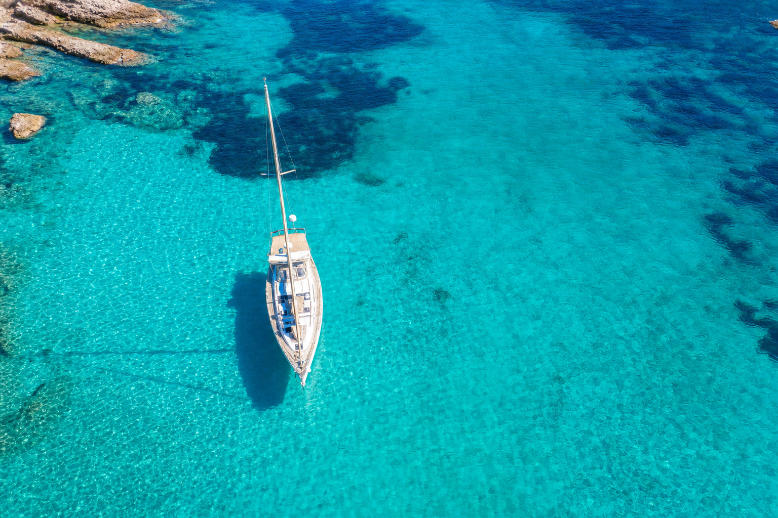 Aerial view of a luxury sailboat in brilliant turquoise Mediterranean waters